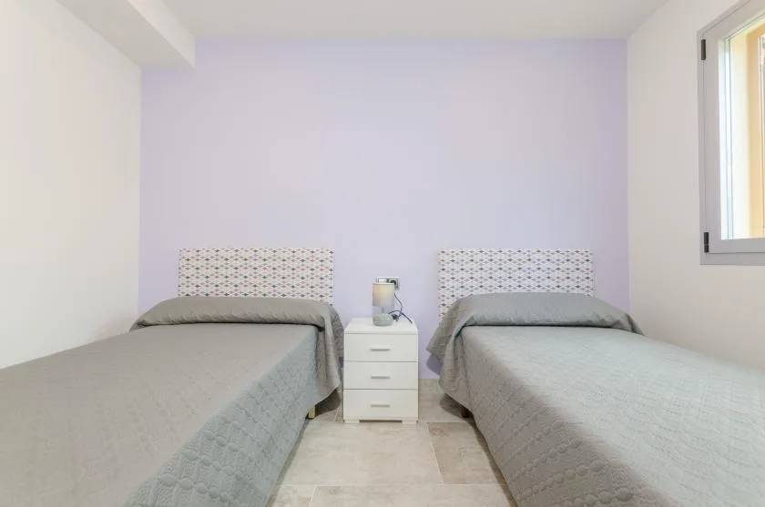 A bedroom with two single beds and a nightstand between them.