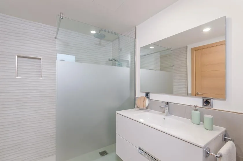 A bright bathroom with a glass shower and a wide sink vanity.