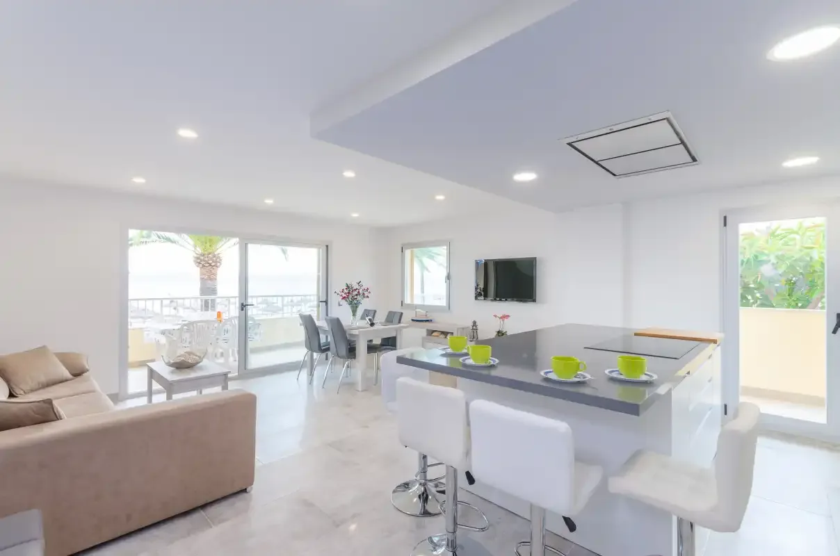 Bright open-plan living and dining area with a kitchen island and sliding glass doors.
