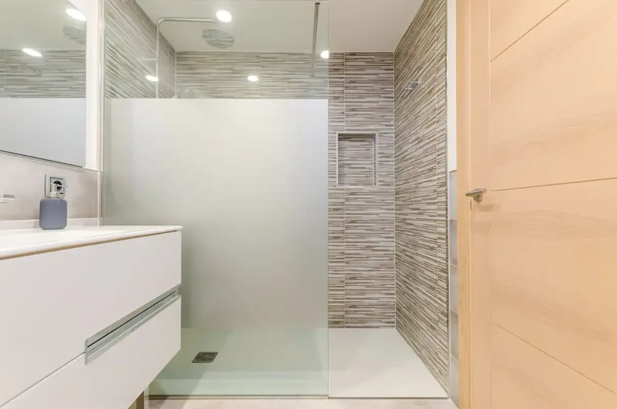A bathroom with a glass shower and a white vanity.