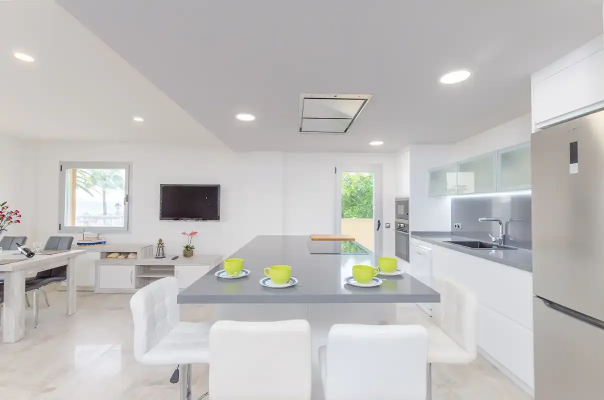 A bright kitchen and dining area with a central island and white seating.