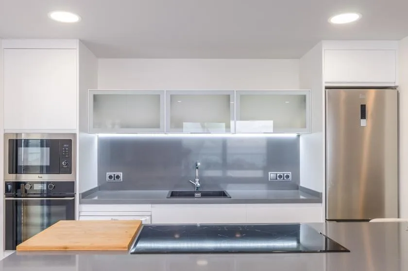 A modern kitchen with a central sink, stainless steel appliances, and a broad countertop.