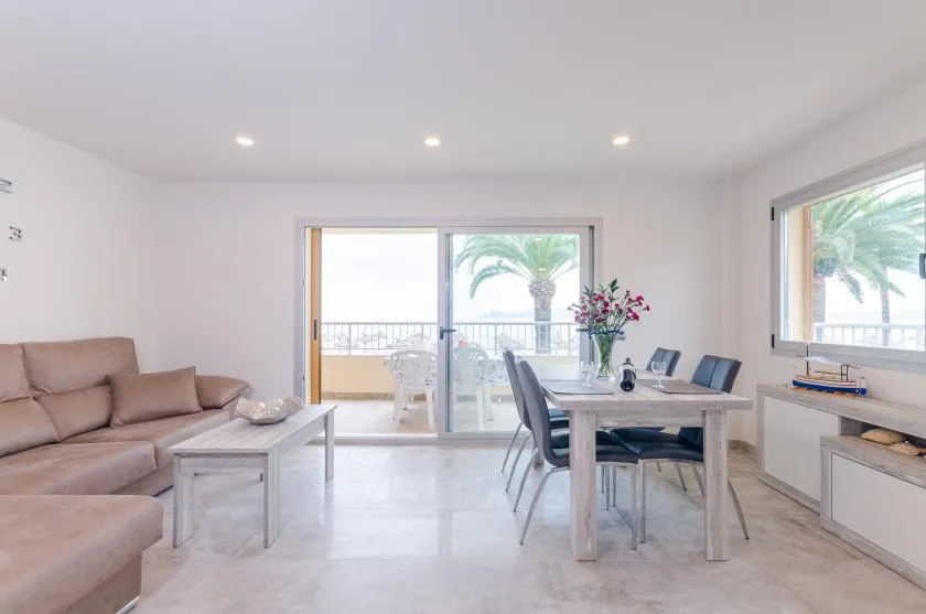 A bright living and dining area opens onto a balcony through sliding glass doors.