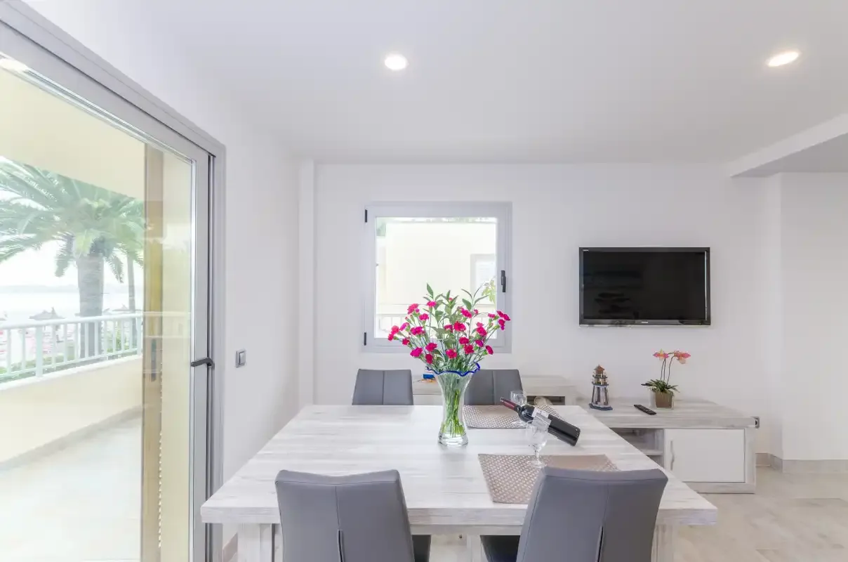 A bright dining area with a table, seating, and a wall-mounted television.