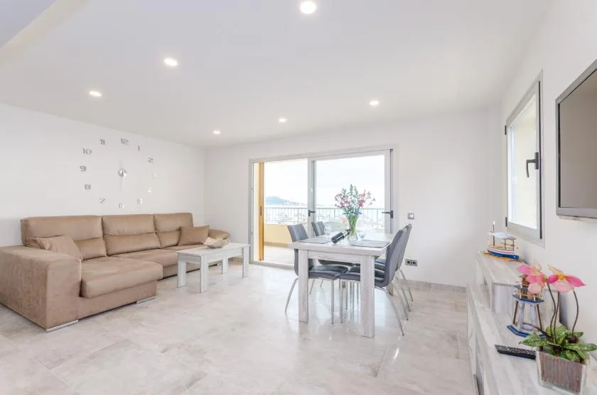 A bright living and dining area with seating beside a glass dining table.