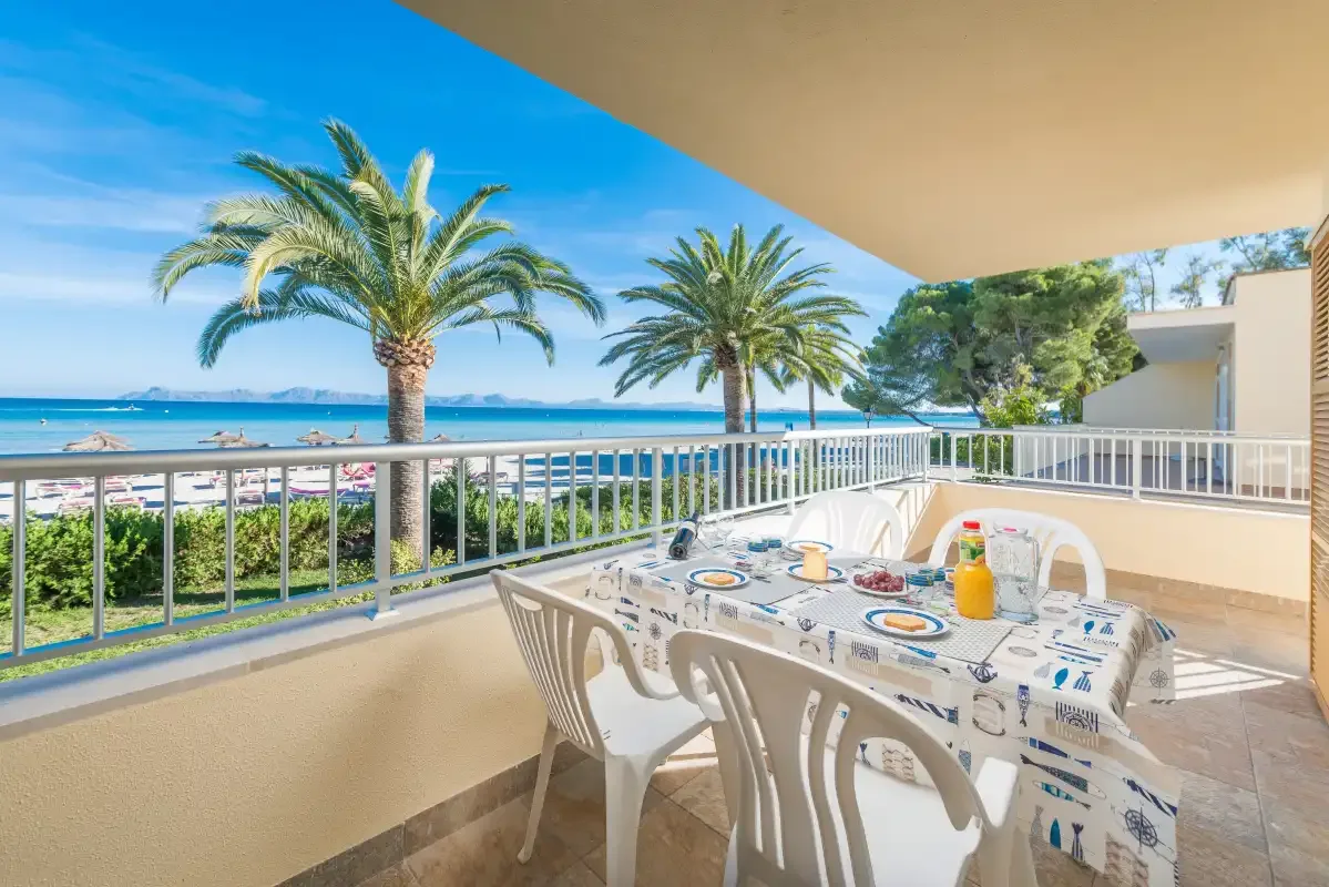 A covered terrace dining area overlooks palm trees and the sea.