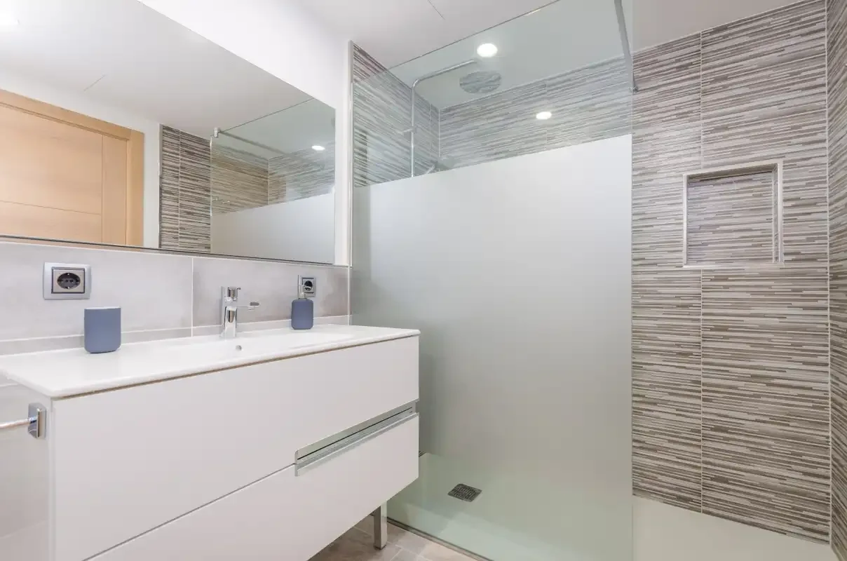 A modern bathroom with a vanity and glass shower.