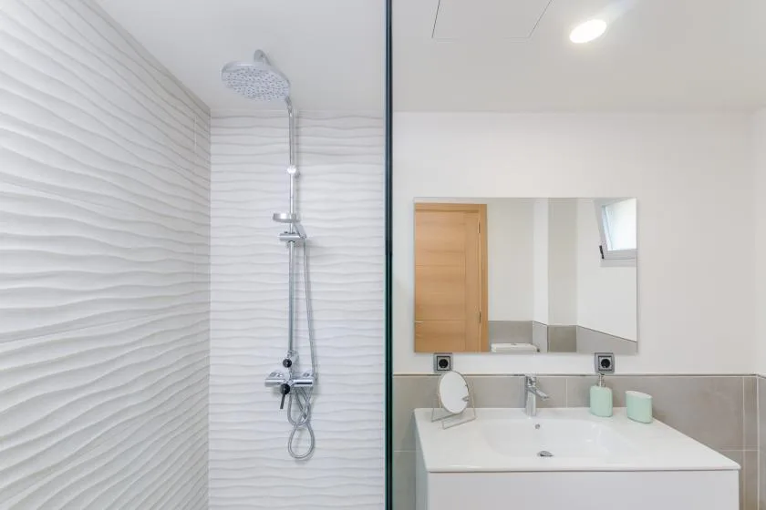 A bright bathroom with a shower and a vanity beneath a wide mirror.