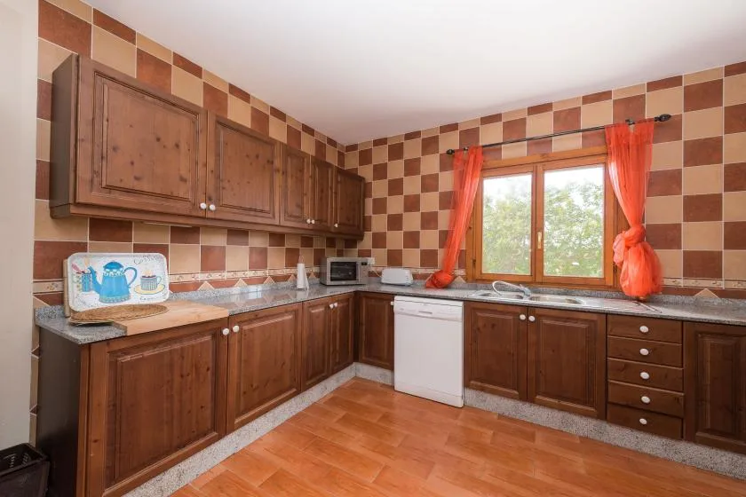 A tiled kitchen with wooden cabinets and a window above the counter.