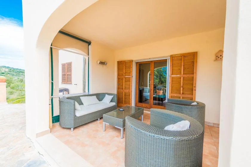 A covered patio with woven seating and a glass door opening onto the garden.