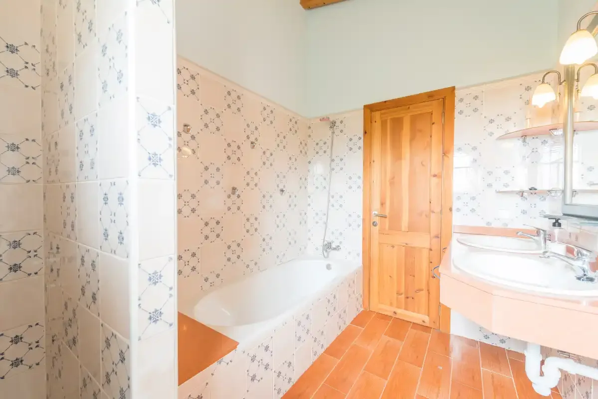 A bathroom with a bathtub, wooden door, and sink.