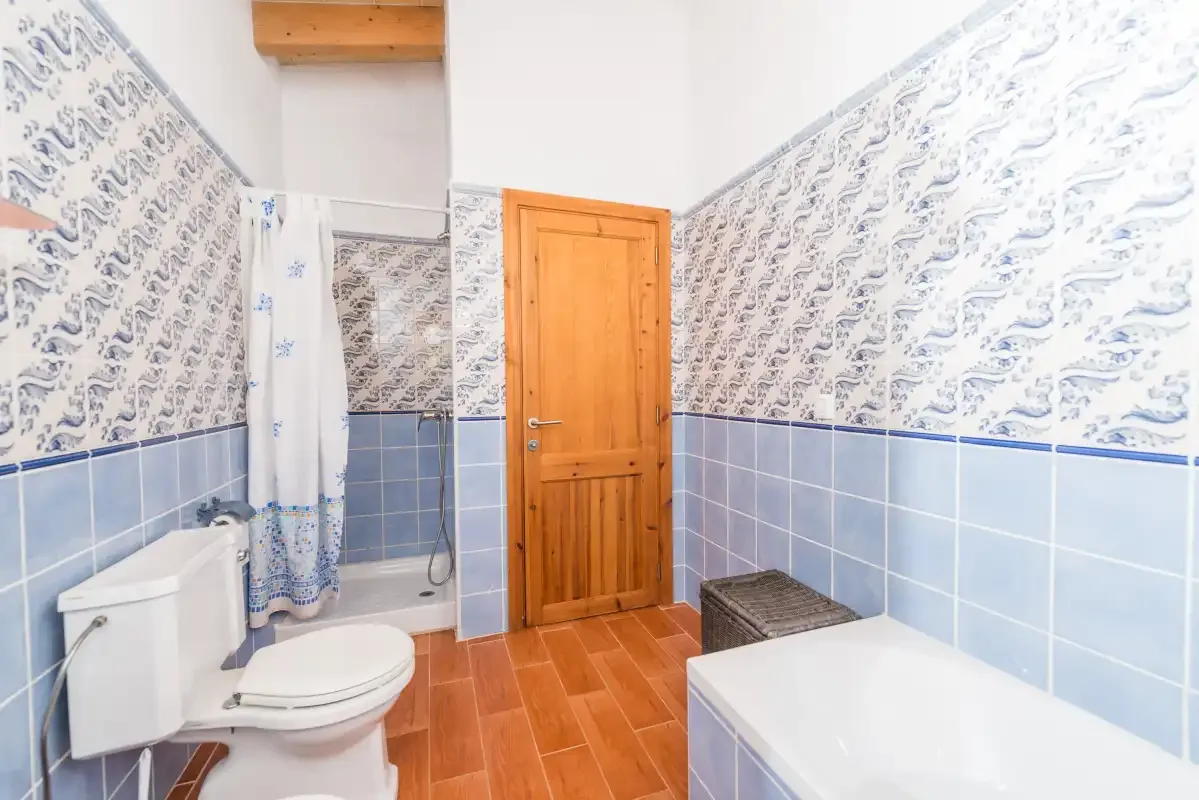 A tiled bathroom with a bathtub, toilet, and wooden door.