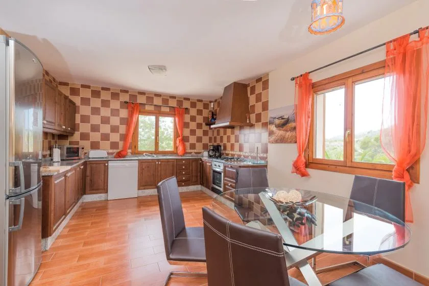 A kitchen and dining area with wooden cabinets and a glass dining table.