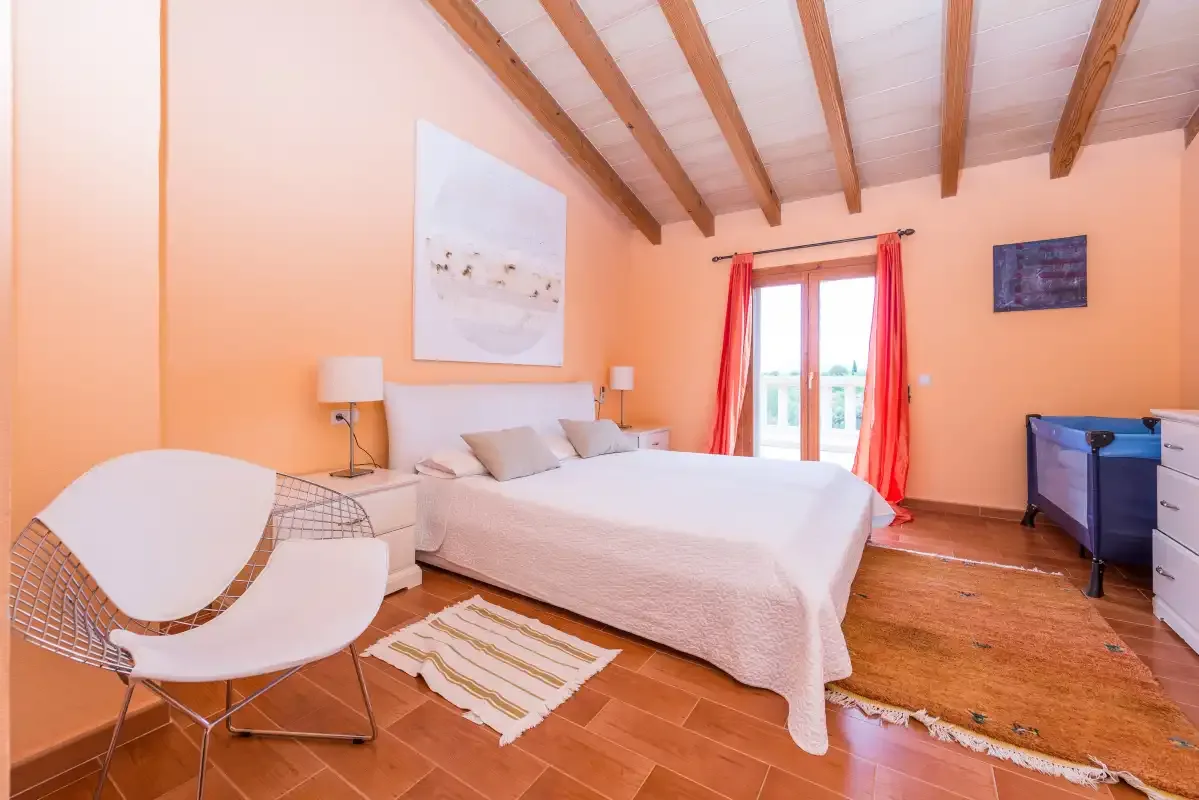 A bedroom with a bed, bedside tables, and red curtains by the window.