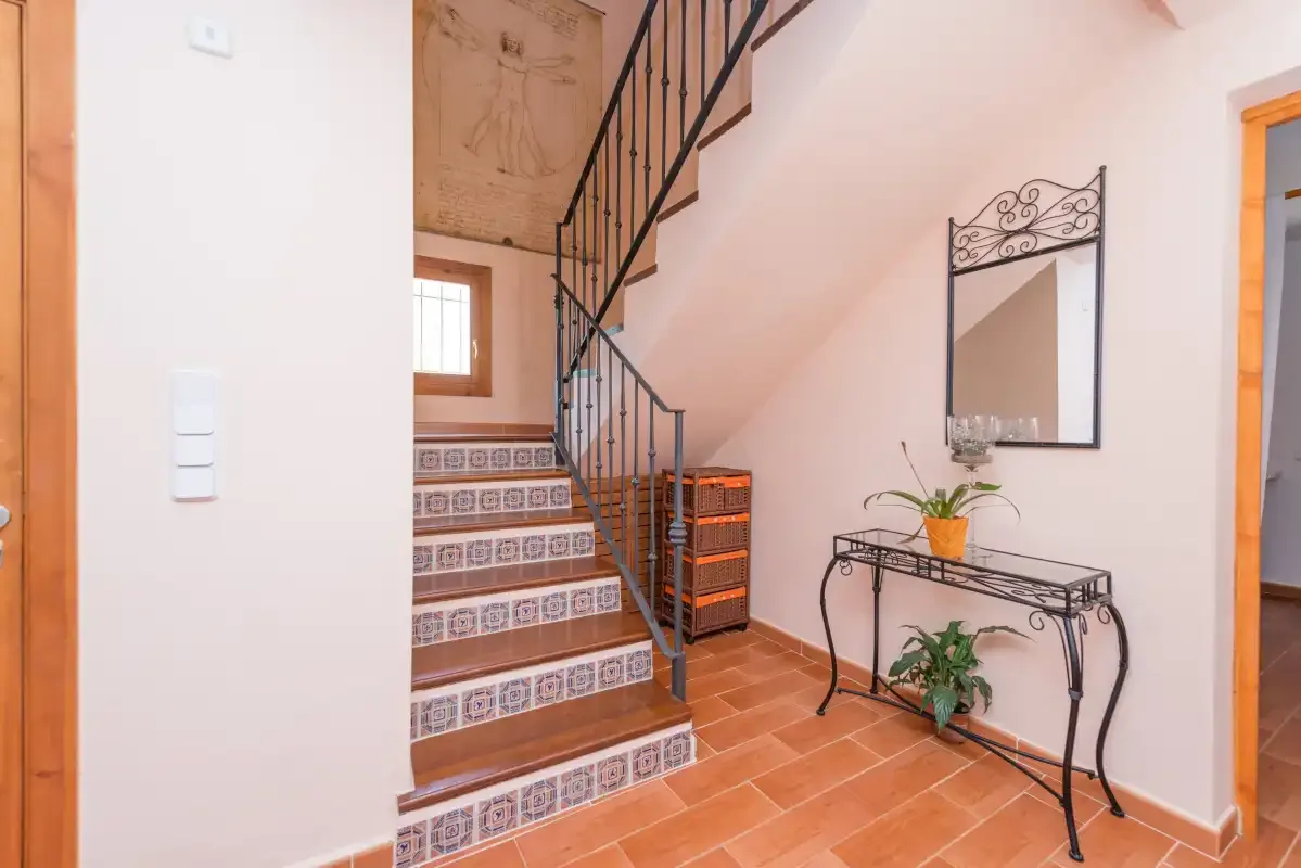 An interior stairway with patterned tile steps and a console table.