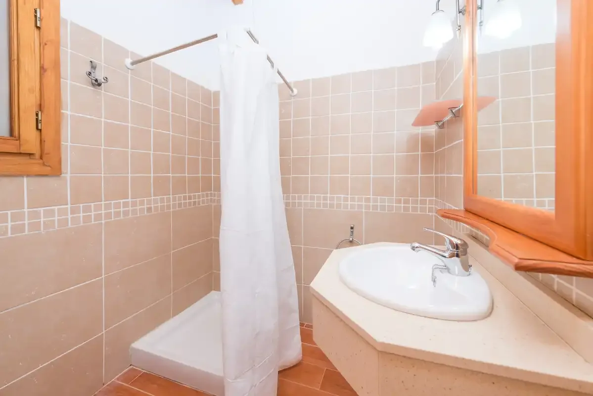 A tiled bathroom with a shower curtain and sink.
