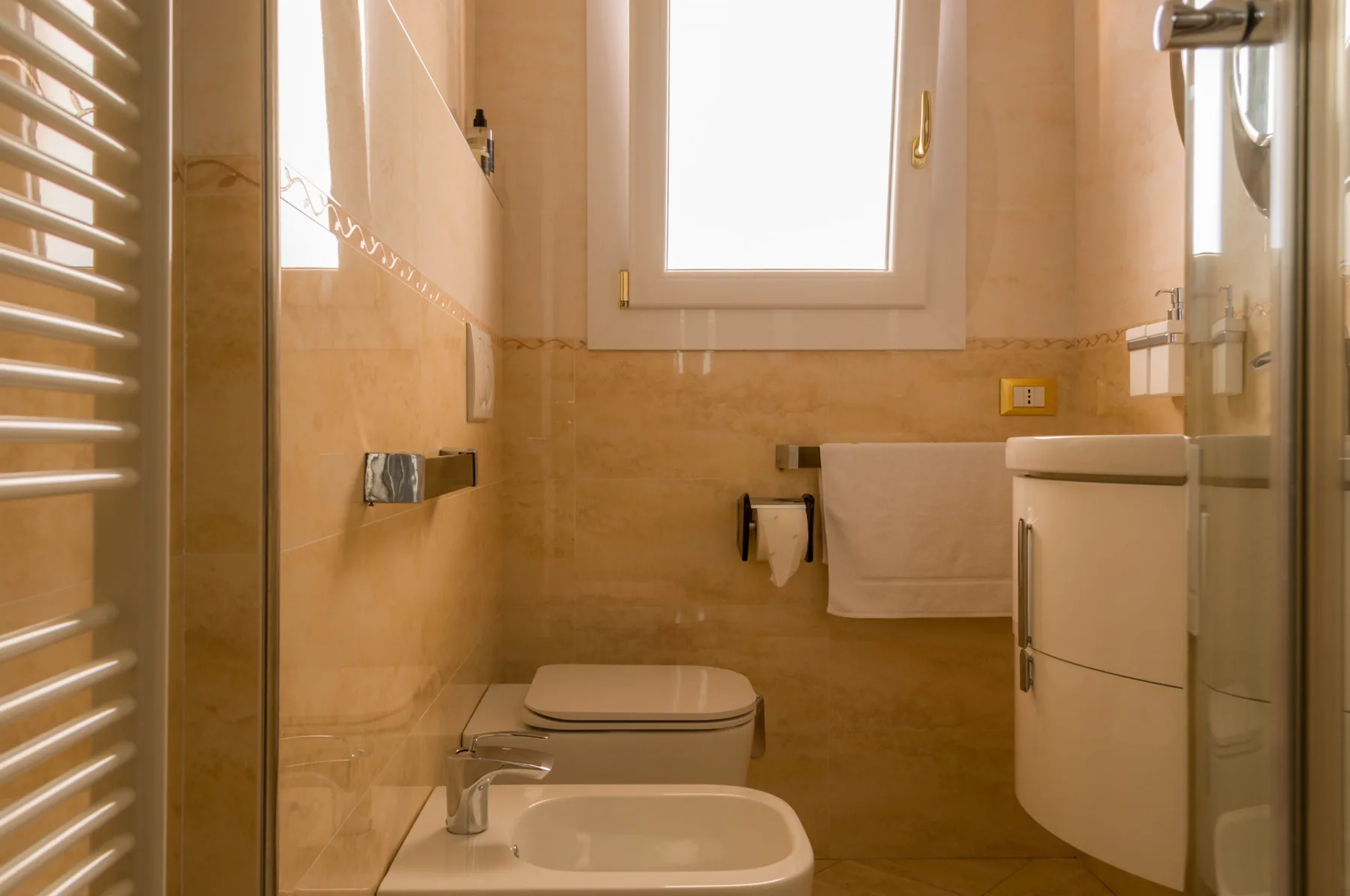 Un baño alicatado con lavabo, inodoro y ventana.