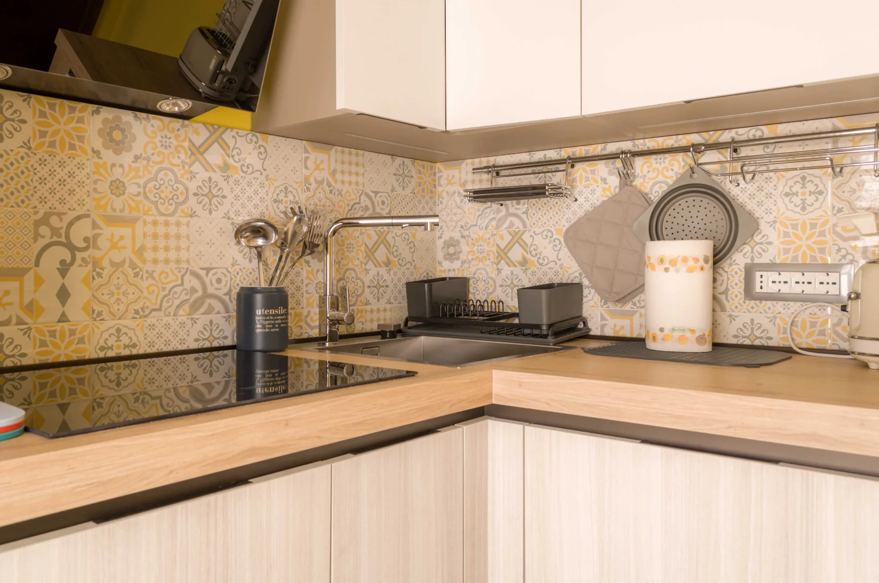 Una cocina con azulejos decorativos en la pared y una placa de cocina sobre la encimera.