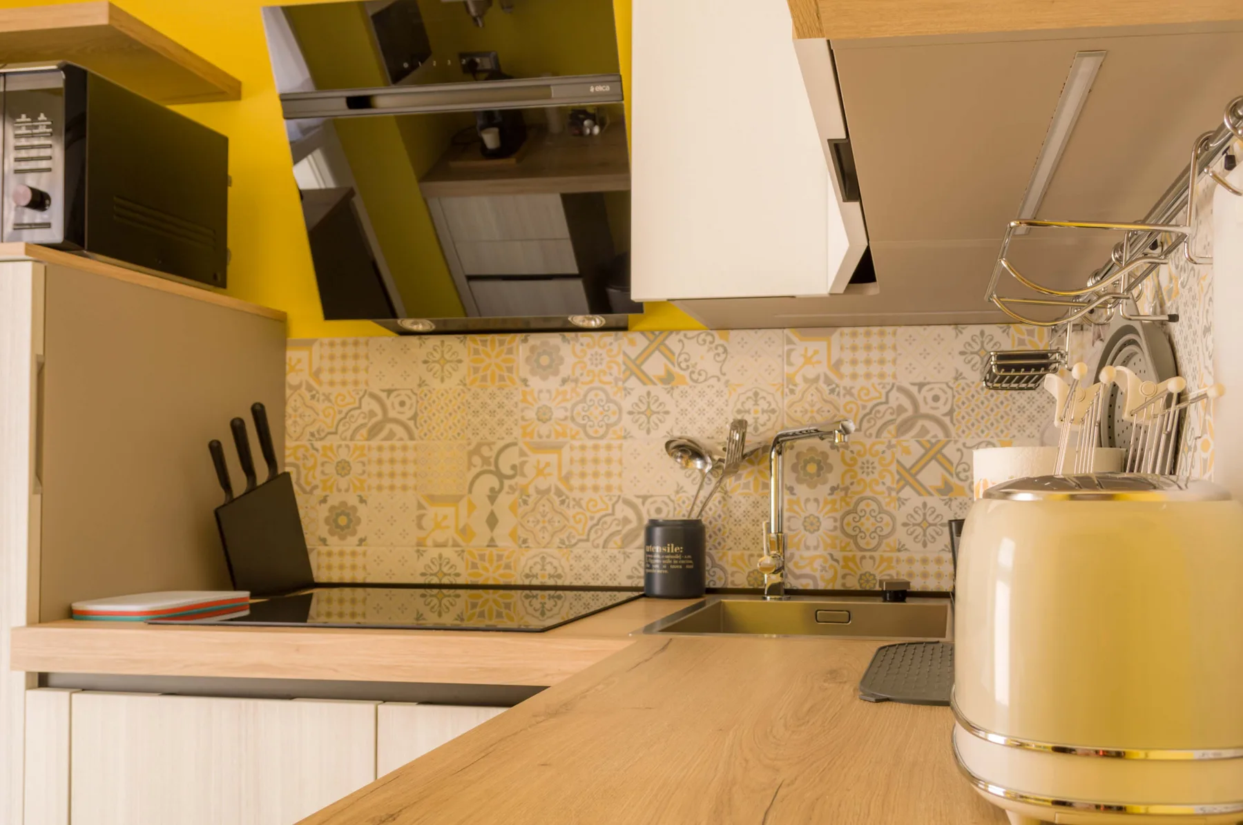 Una cocina compacta con fregadero, salpicadero estampado y electrodomésticos sobre la encimera.