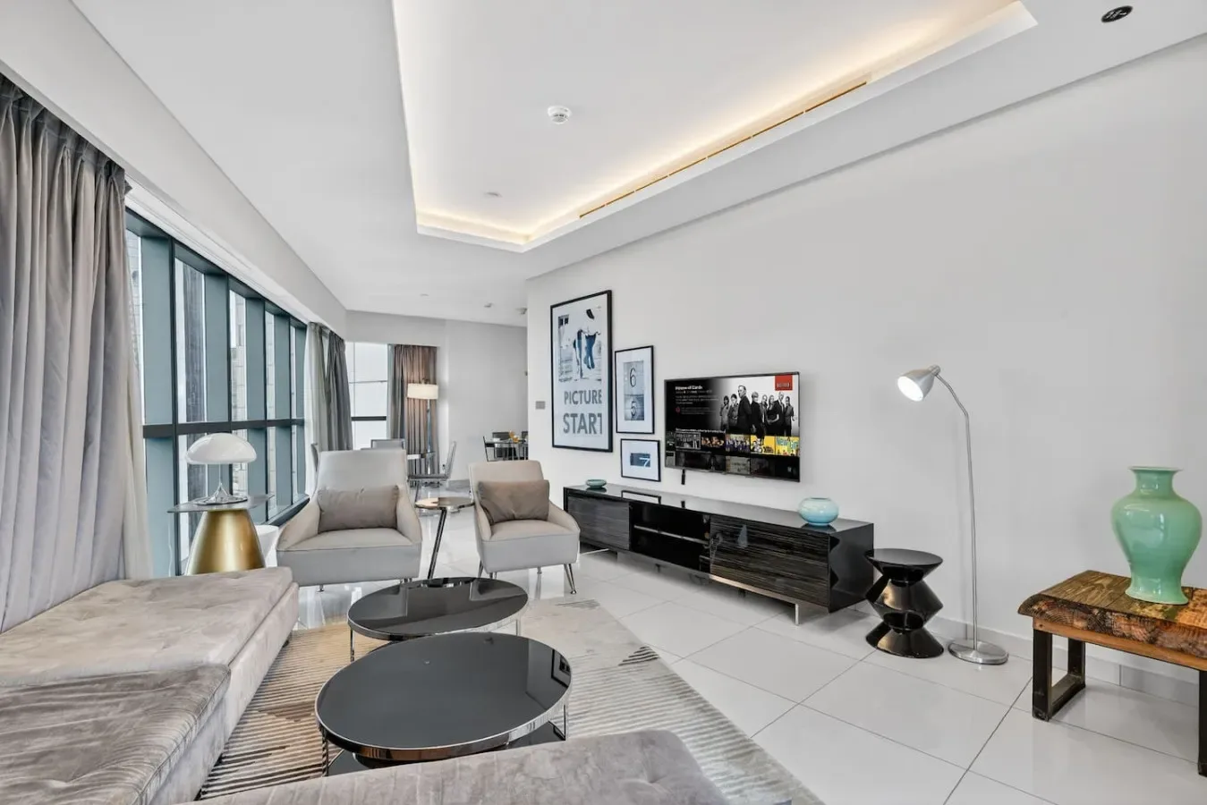 A bright living room with seating, a television, and large windows.