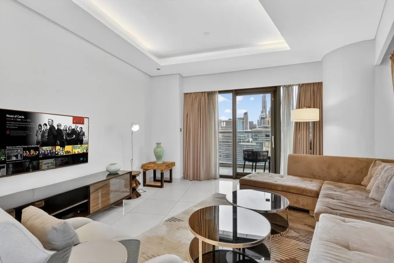 A bright living room with a television, seating, and large windows.