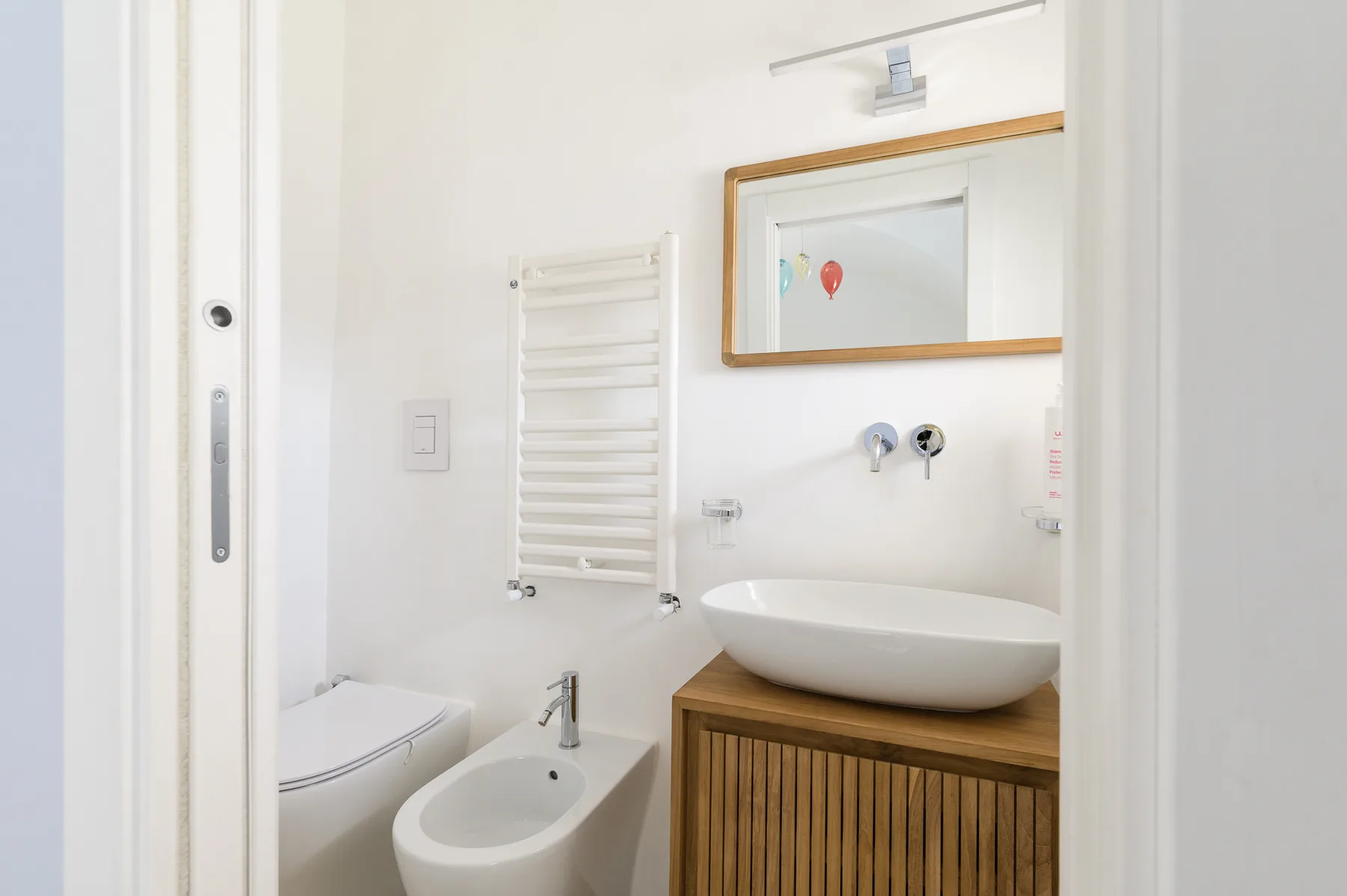 Un baño luminoso con lavabo, inodoro y toallero calefactable de pared.