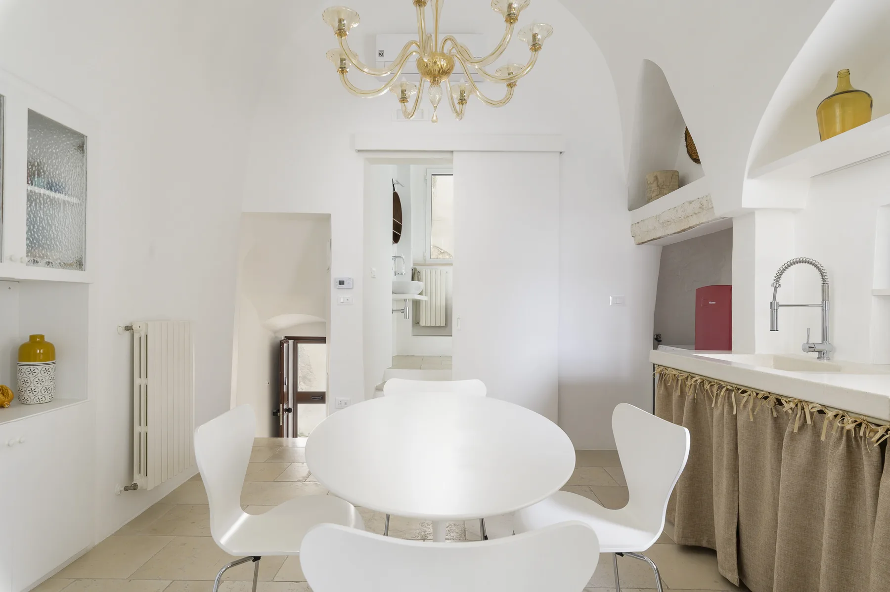 Un comedor luminoso con una mesa redonda y una encimera de cocina junto a la pared.