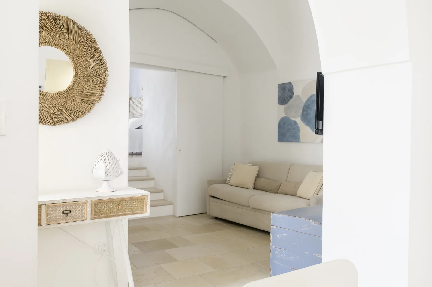 A bright living room with a beige sofa beneath an arched ceiling.
