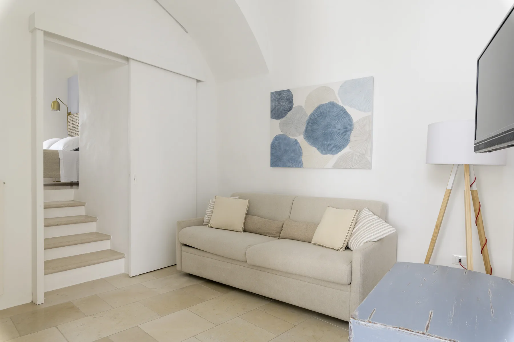 A bright living room with a beige sofa beneath abstract wall art.