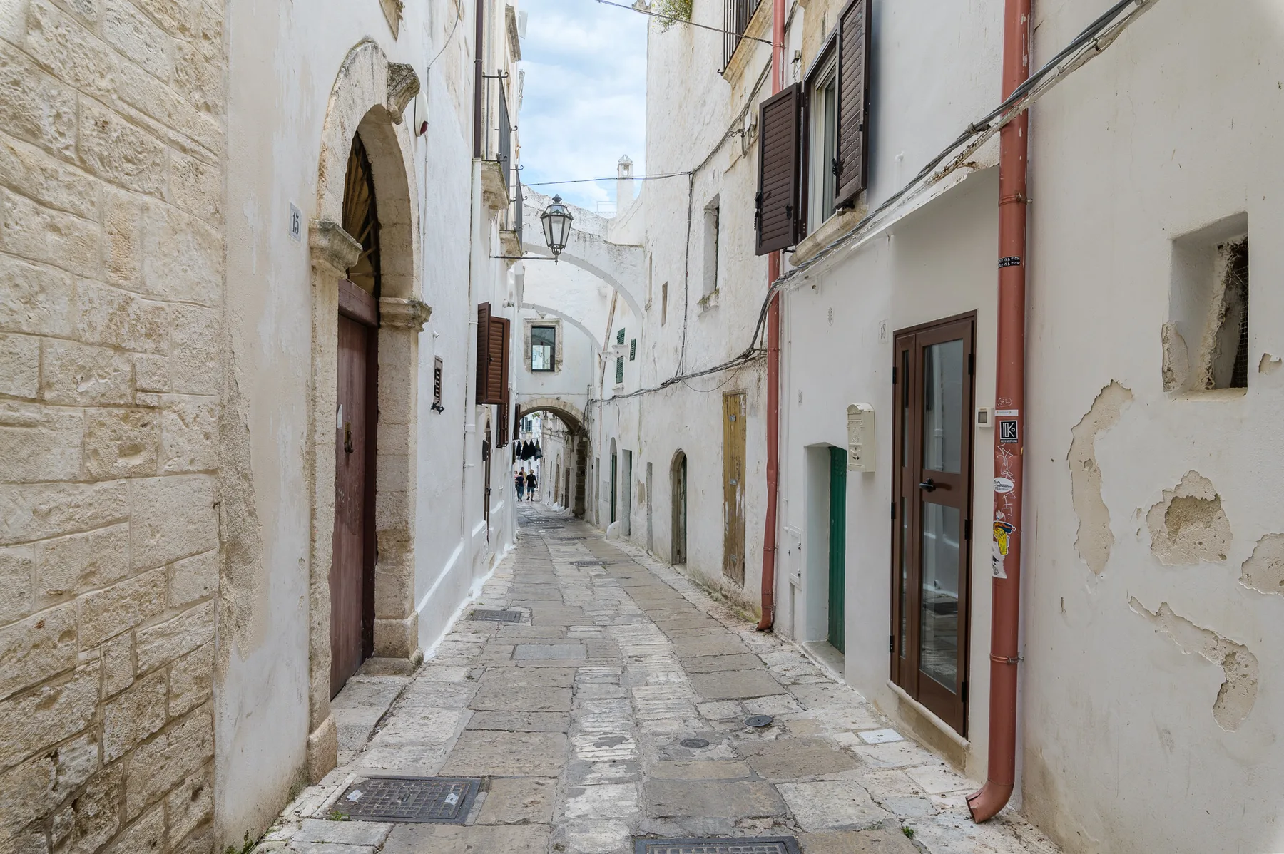 Un estrecho callejón empedrado pasa entre edificios encalados con puertas arqueadas.