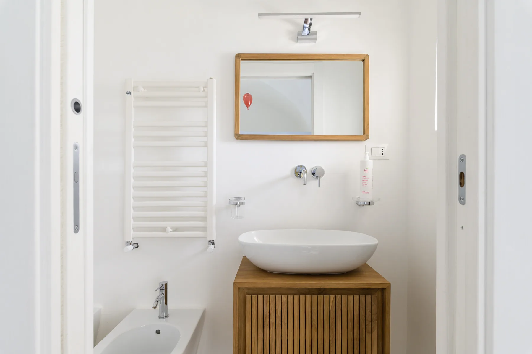 Un baño luminoso con un lavabo de sobremesa y un toallero calefactable.