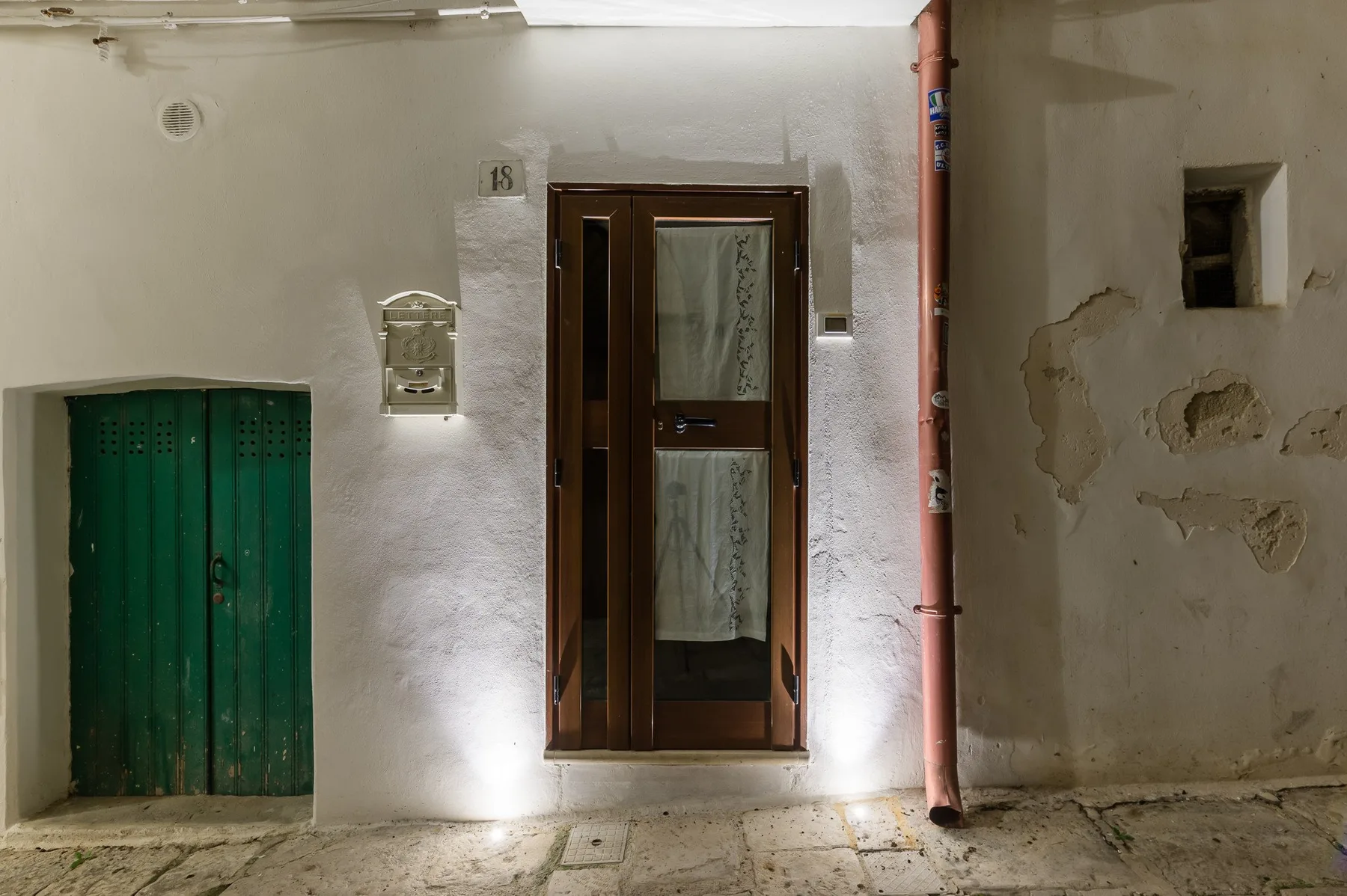 Una entrada exterior con una puerta de madera oscura en una pared blanca.