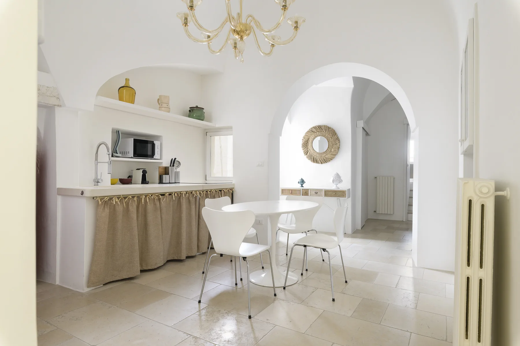 A bright dining area with a table and chairs beside an arched doorway.