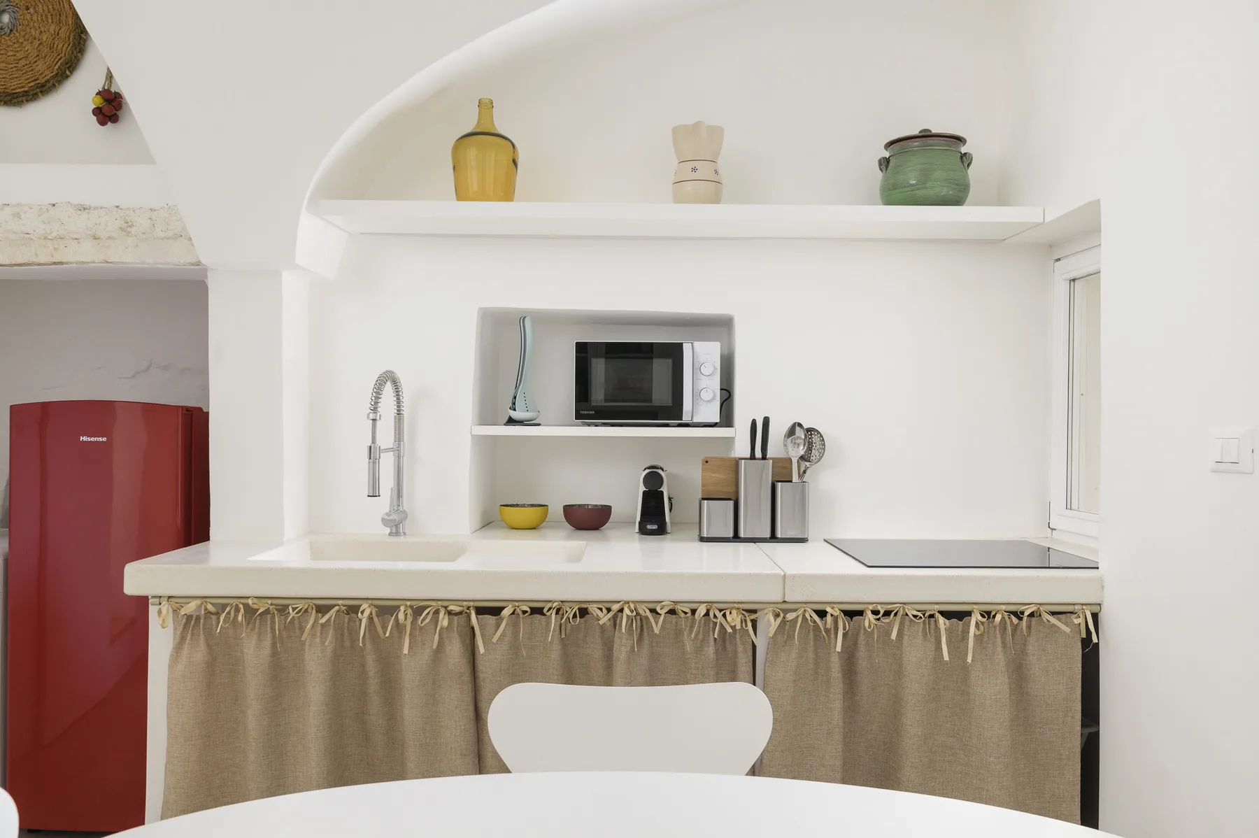 Una cocina compacta con encimera, fregadero, microondas y refrigerador rojo.