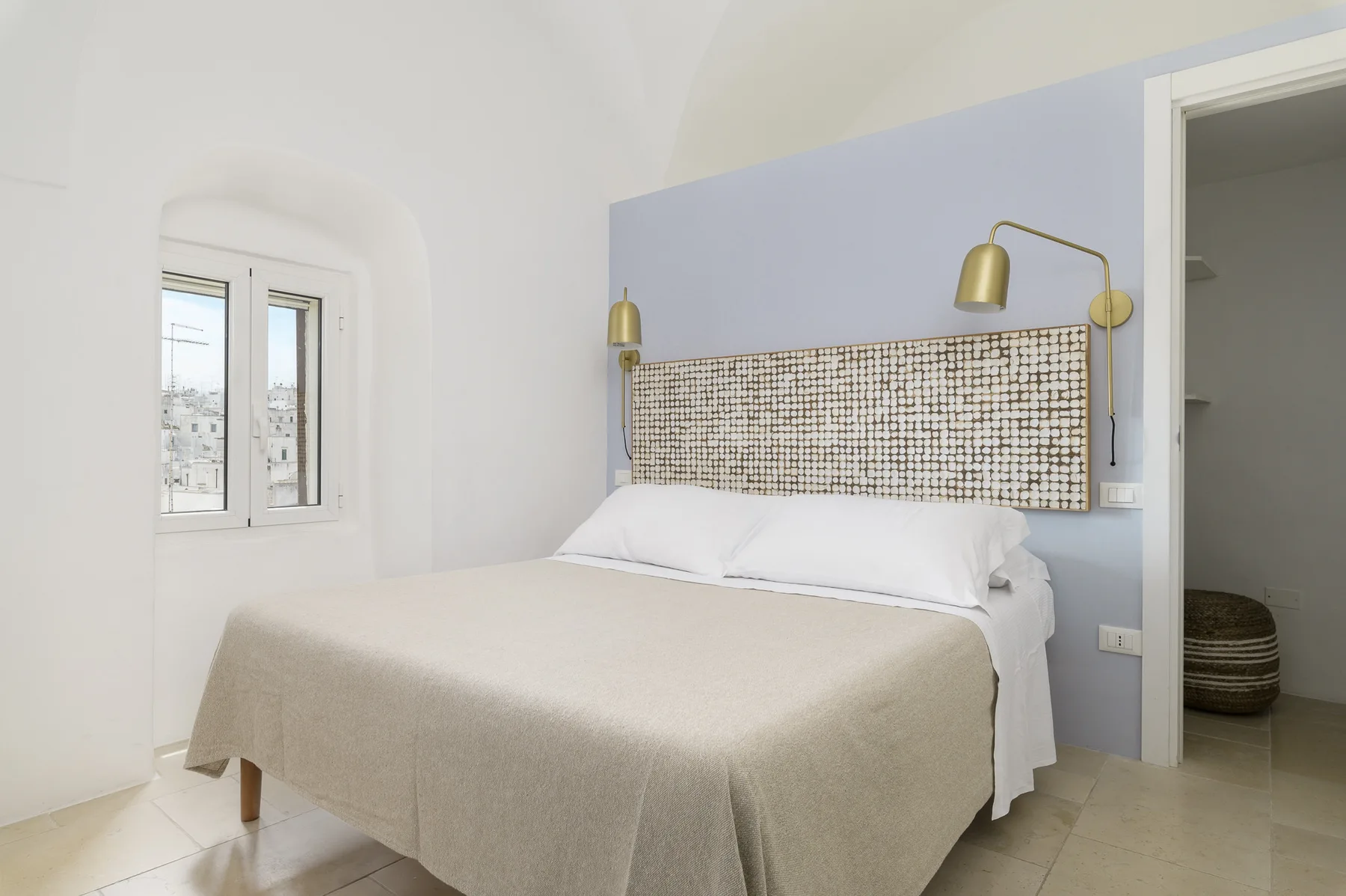 Un dormitorio luminoso con una cama frente a una pared de acento azul claro.