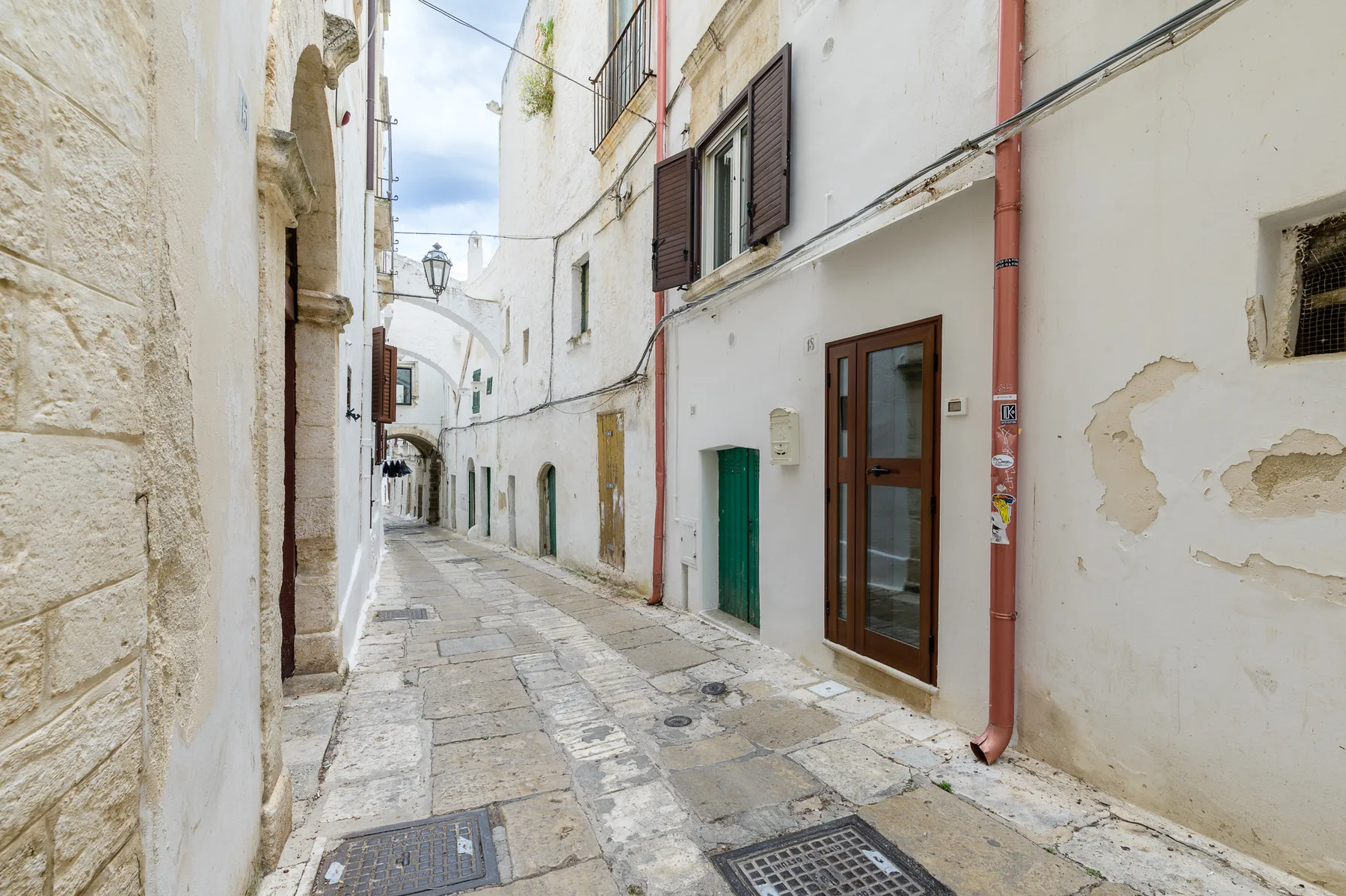Una calle estrecha pavimentada con piedra pasa entre edificios blancos muy próximos.