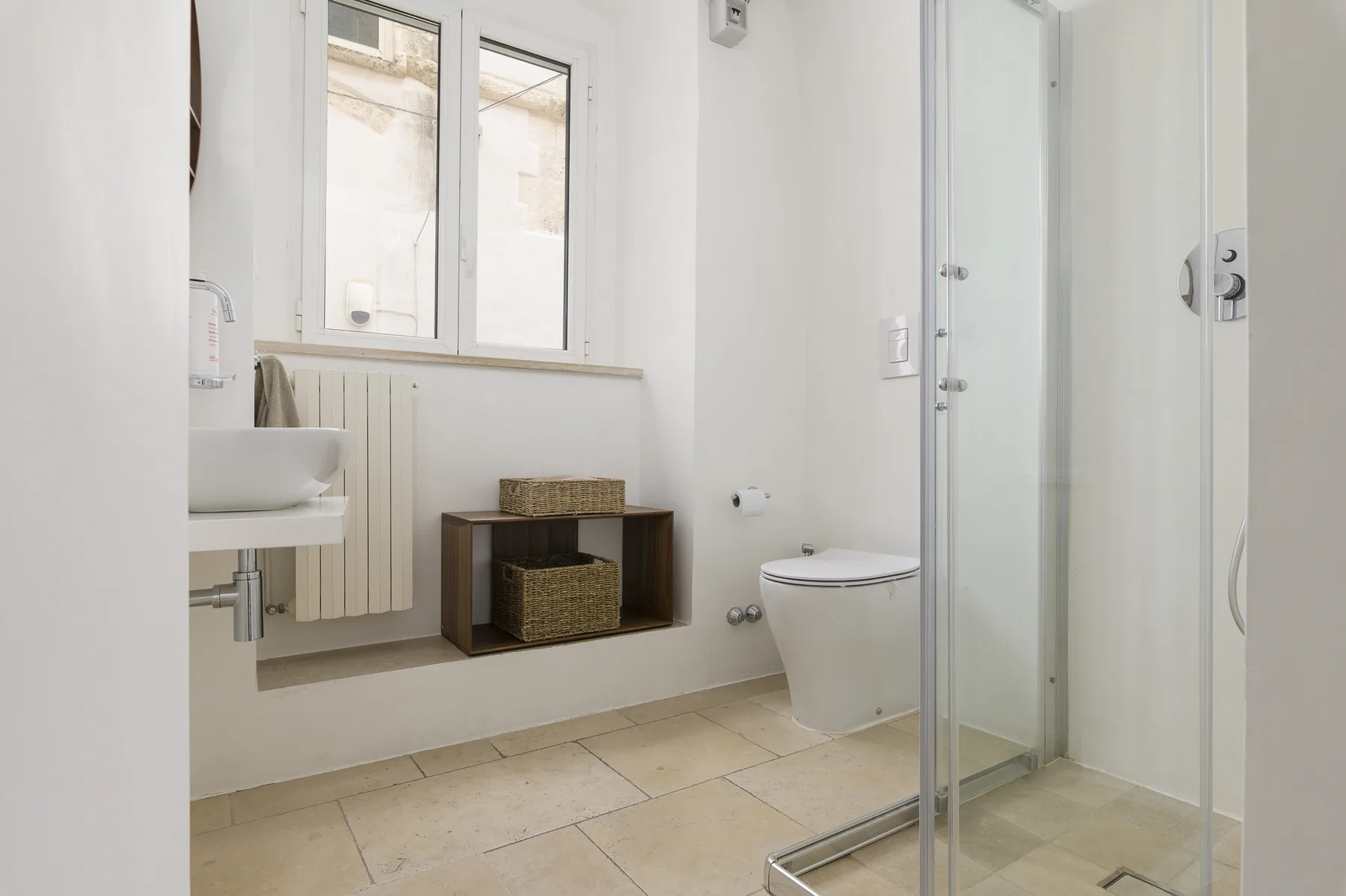 Un baño luminoso con lavabo, inodoro y ducha de cristal.