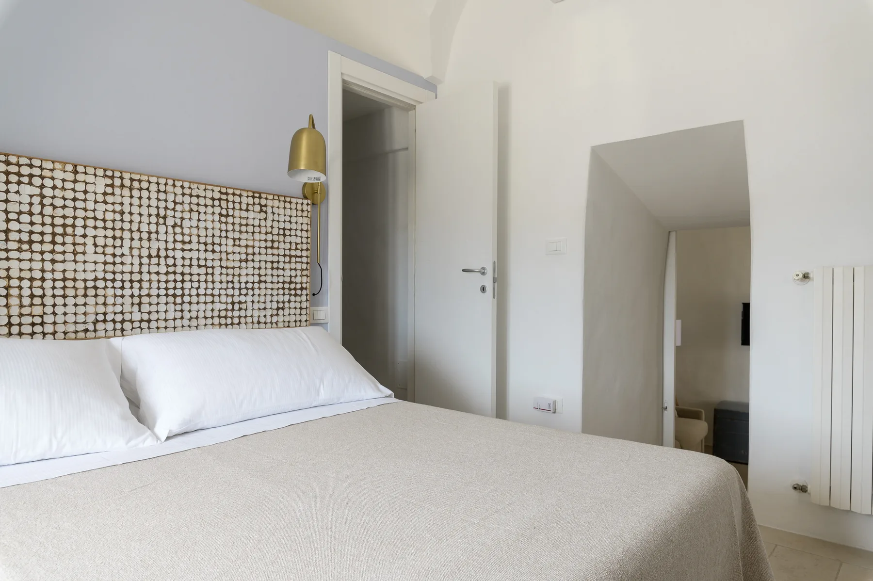 Un dormitorio con una cama, un cabecero estampado y una puerta abierta.
