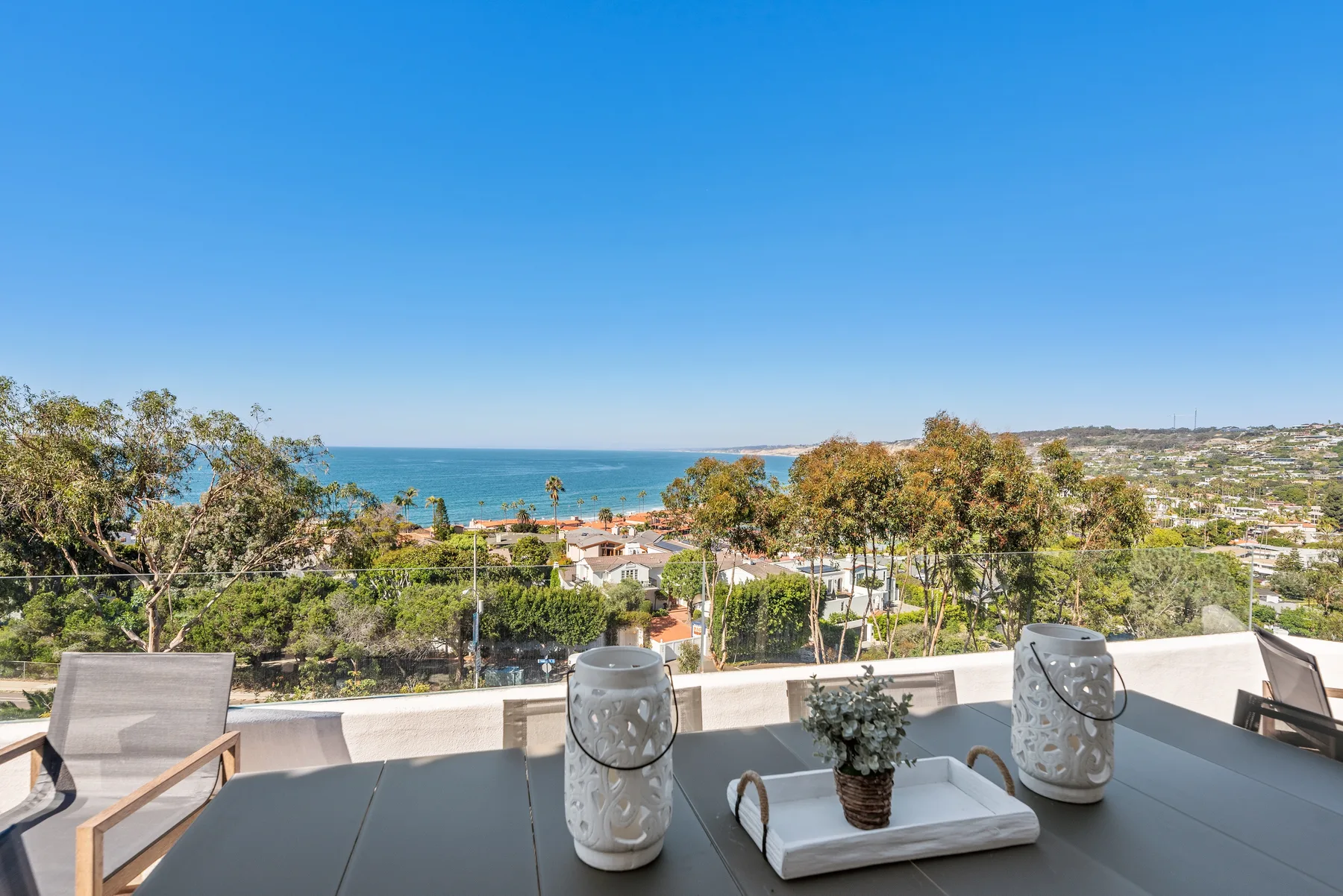 Una terraza ofrece vistas al mar, con asientos y plantas en macetas en primer plano.