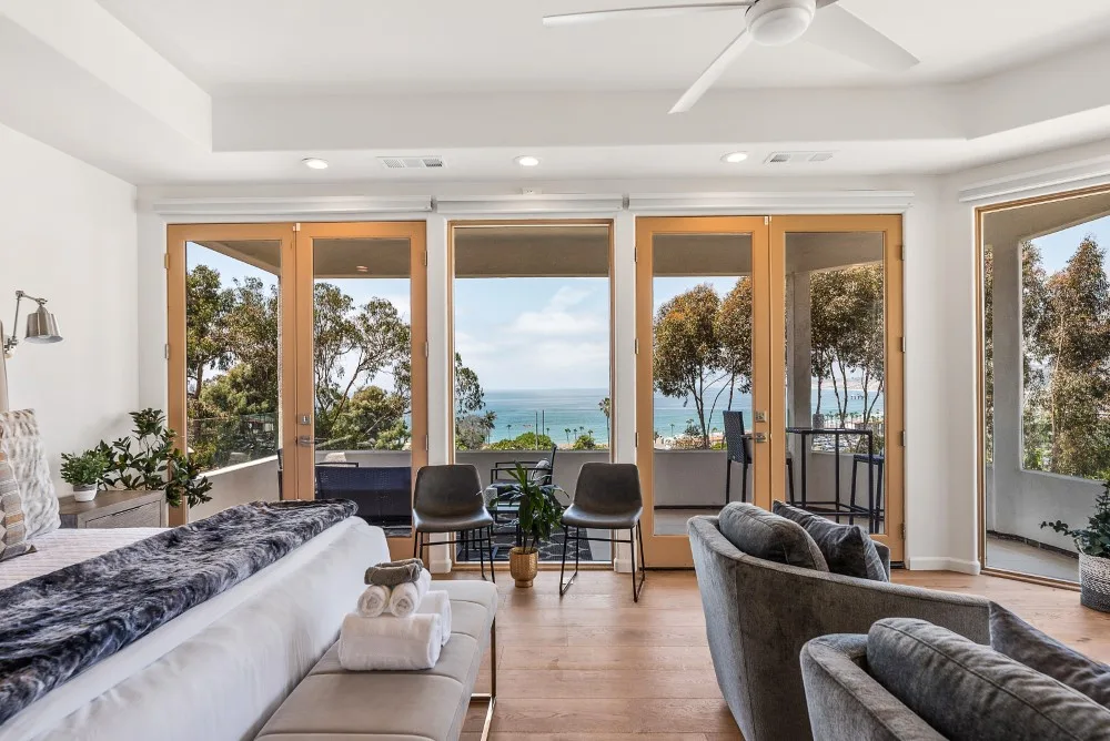 Una luminosa zona de estar en un dormitorio se abre a amplias ventanas con vistas al mar.