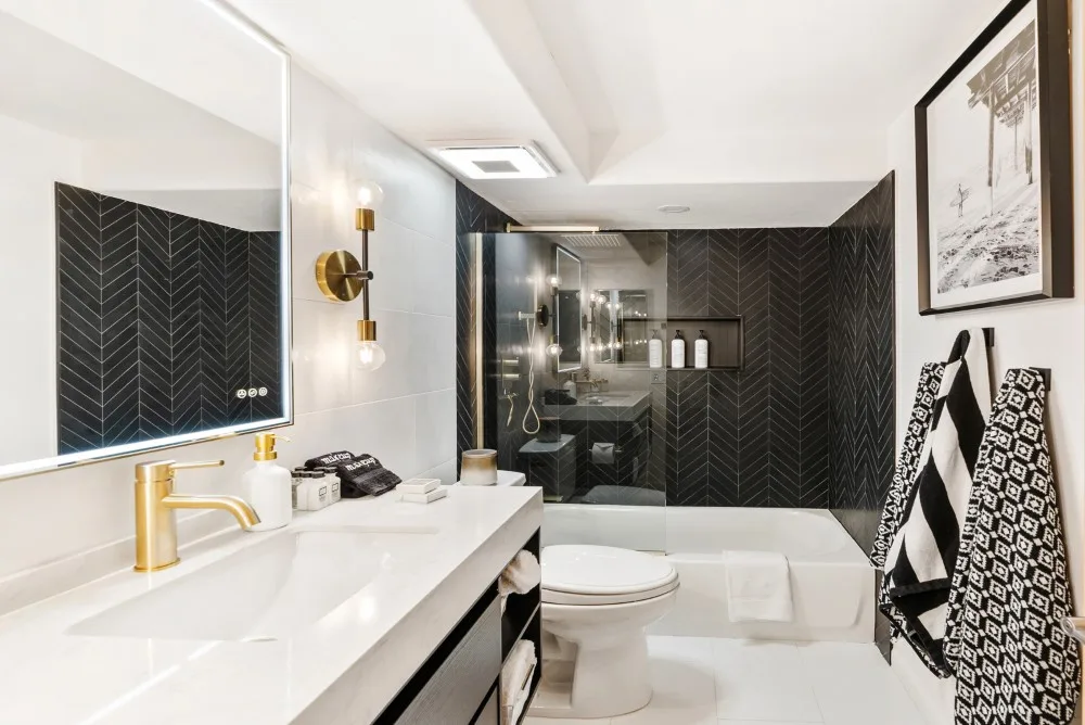 Un baño luminoso con un tocador largo, inodoro y bañera.