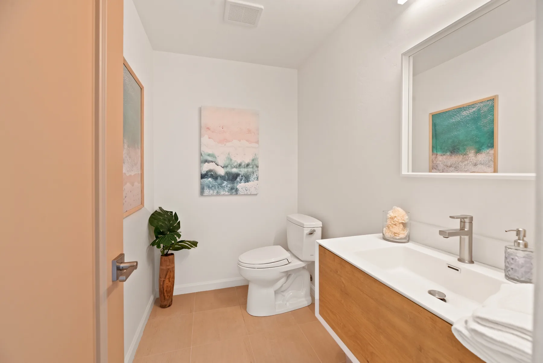 Un baño luminoso con inodoro, tocador y cuadros enmarcados.