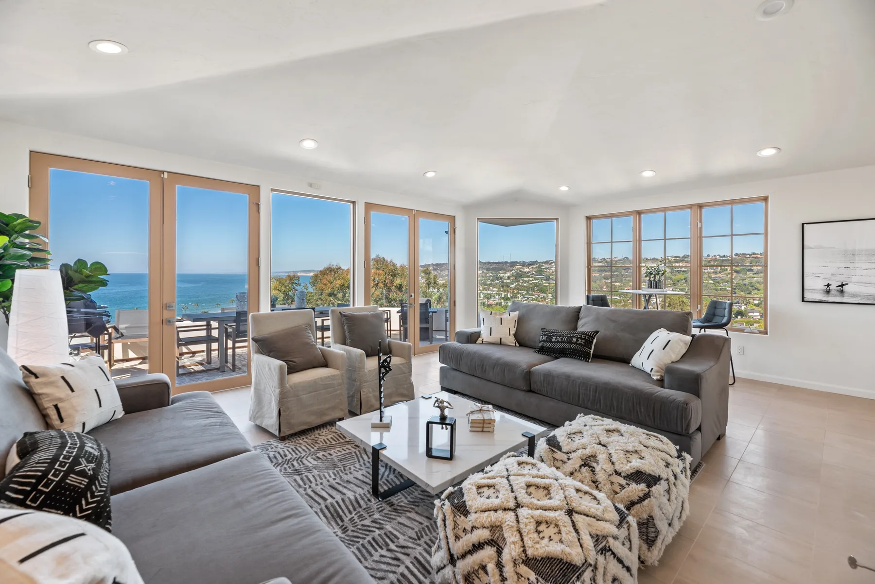 Una sala luminosa con asientos grises, grandes ventanas y vistas a la costa.