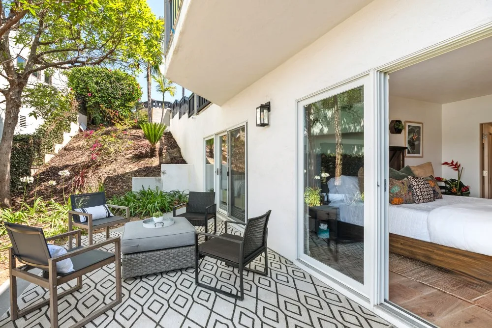 Un patio amueblado junto a un dormitorio con puertas corredizas de vidrio abiertas.