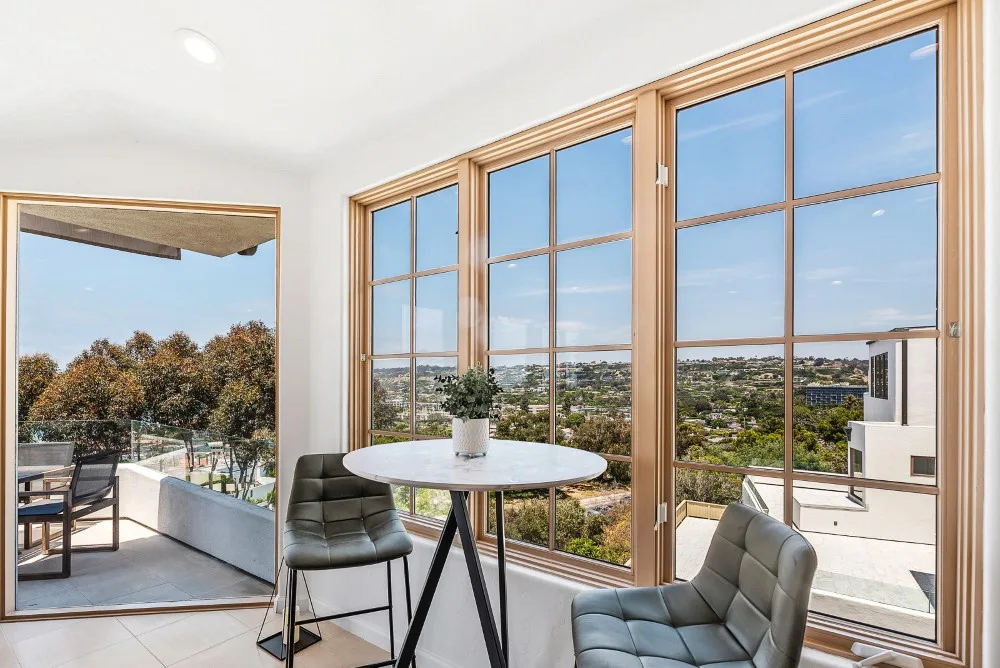 Un solárium luminoso con ventanales altos y una mesa pequeña con vistas al paisaje.
