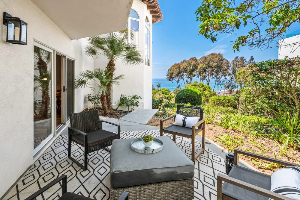 Un patio exterior con asientos da a un jardín paisajístico y al mar.