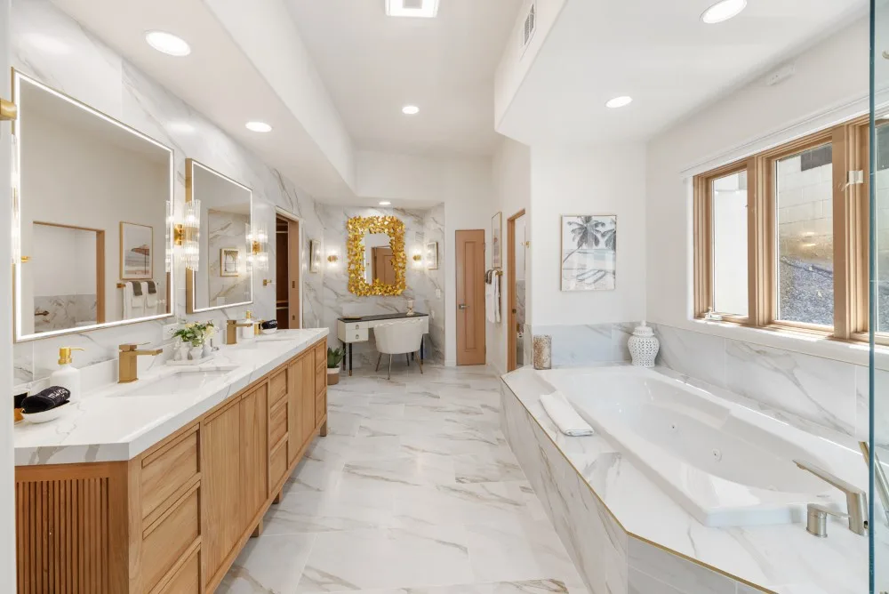 Un baño luminoso cuenta con un tocador largo y una bañera amplia.
