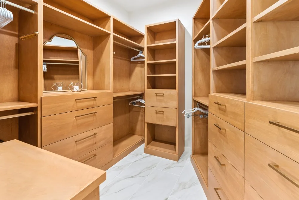 Un vestidor con estantes de madera, cajones y un suelo claro.