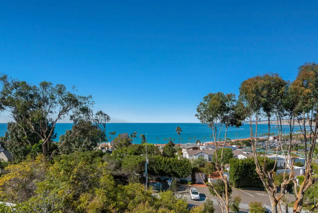Un barrio costero mira al mar bajo un cielo azul despejado.