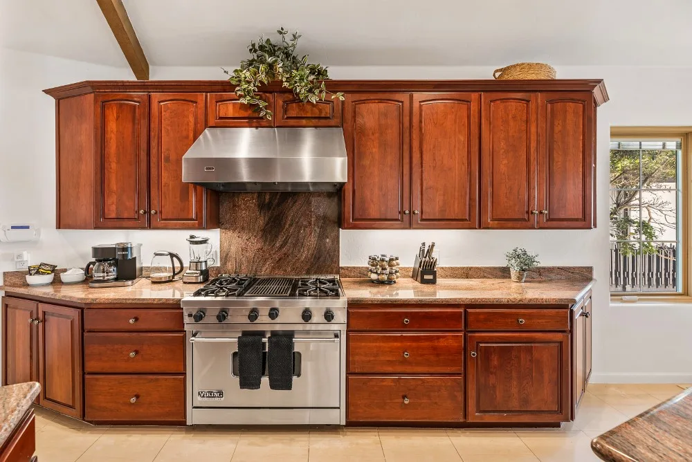 Una cocina con gabinetes de madera, una estufa y una campana de acero inoxidable.